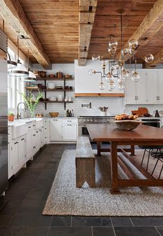 a kitchen with white cabinets and wood ceilinging, an island table in the middle