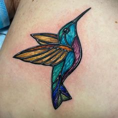 a colorful hummingbird tattoo on the back of a woman's stomach