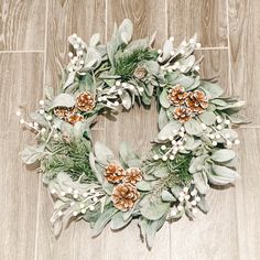 a christmas wreath on the floor with pine cones and greenery around it, ready to be decorated