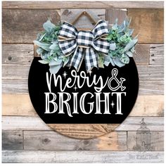 a merry and bright sign hanging on the side of a wooden wall with succulents