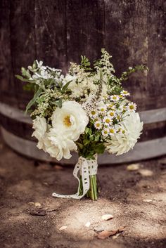 a bouquet of white flowers sitting in front of a barrel