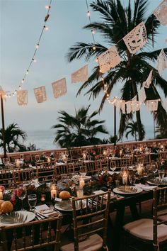 an outdoor dining area with tables and chairs set up for dinner at the beach side