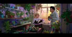 a man and woman standing in a room full of potted plants next to each other