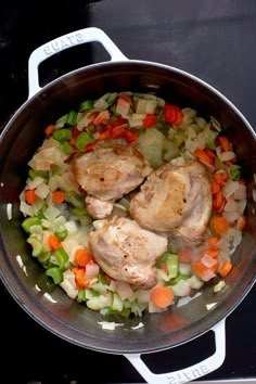 chicken, carrots and celery are cooking in a pot on the stove