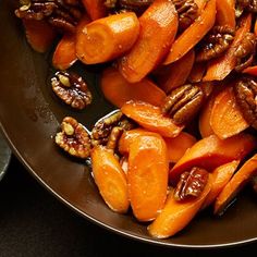 sliced up carrots and pecans in a brown bowl on a black counter top