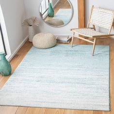 a chair and mirror in a room with wood flooring on the ground, along with a blue rug