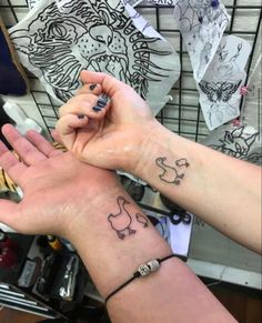 two people holding hands with tattoos on them