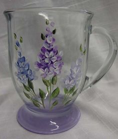 a glass mug with purple flowers painted on it