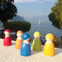 four wooden pegs sitting on top of a stone wall next to the water and trees