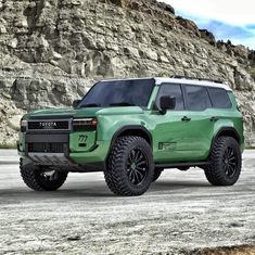 a green truck parked in front of a mountain