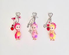 three key chains with cartoon characters on them, one is pink and the other is yellow