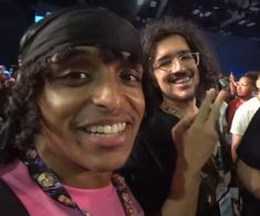 two men standing next to each other in front of a crowd at a convention or show