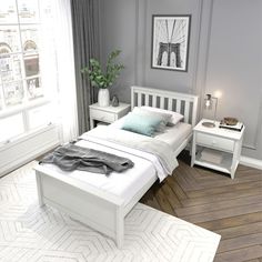 a white bed sitting next to a window in a room with hardwood floors and gray walls