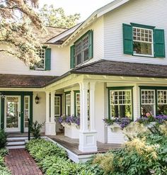 a white house with green shutters and flowers