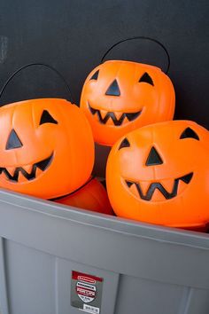 three carved pumpkins sitting in a trash can