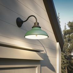 an outdoor light on the side of a house next to a garage door and tree