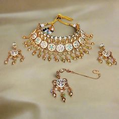 Enhance your bridal look with this exquisite Copper Rajwadi Necklace Set, a perfect blend of traditional craftsmanship and royal elegance. The set includes a stunning choker necklace intricately designed with detailed copper work, featuring sparkling stone embellishments. The delicate dangle design is adorned with pastel-colored beads, adding a subtle pop of color to the rich gold-tone finish. This set comes complete with matching earrings, a maang tikka for a complete regal look. Ideal for weddings, festive occasions, or any grand celebration, this Rajwadi set is a must-have for those who love to embrace heritage and sophistication in their jewelry collection. Key Features: - Traditional copper finish with intricate detailing - Complete set includes choker necklace, earrings and maang tik Traditional Bridal Jewelry, Copper Work, Necklace Set With Earrings, Pastel Beads, Maang Tikka, Bridal Look, Bridal Looks, Matching Earrings, Necklace Set