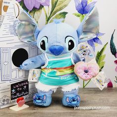 a blue stuffed animal next to a cardboard box with flowers on it and a donut