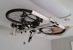 a bicycle is mounted to the ceiling in a room with white walls and carpeting