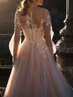 a woman in a wedding dress standing near a lamp post with her back to the camera