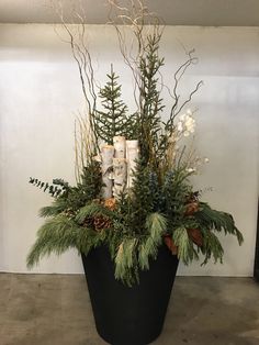 a planter filled with evergreen, pine cones and candles