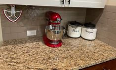 a red mixer sitting on top of a kitchen counter