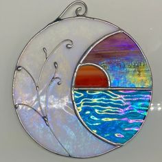 a stained glass sun and moon hanging on the side of a white wall next to a body of water