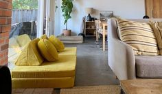 a living room filled with furniture next to a brick wall covered in plants and potted plants