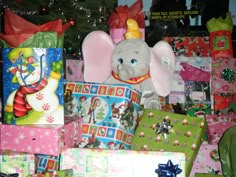 a stuffed elephant sitting next to presents under a christmas tree