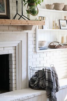 a living room with white brick fireplace and potted plants on the mantel above it