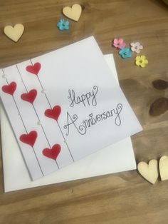 an anniversary card with hearts and flowers on the table next to it is written happy anniversary