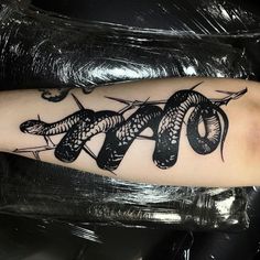 a black and white snake tattoo on the arm