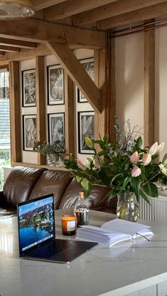 a laptop computer sitting on top of a table next to a vase filled with flowers