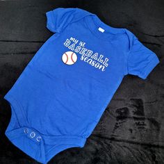 Is this your first baseball season? Is it time to take baby to their first baseball game? Featuring a decal in white, black, and red. Infant bodysuits are Bella Canvas 4.2 oz, 100% combed and ring spun cotton. Snap leg closures, envelope neck and side seamed. Available in sizes 3-6 mo, 6-12 mo, 12-18 mo and 18-24 mo. 0-3 available upon request and availability. Care Instructions:  Preshrunk cotton. Wash inside out. Cool water with like colors. Tumble dry low or hang to dry. Casual Onesie With Letter Print For Game Day, Sporty Onesie With Letter Print For Sports, Casual Sports Onesie With Letter Print, Casual Cotton Onesie For Sports Events, Sports Cotton Onesie With Short Sleeves, Cotton Onesie With Letter Print For Sports Events, Casual Sports Onesie With Short Sleeves, Casual Short Sleeve Sports Onesie, Casual Cotton Onesie For Game Day