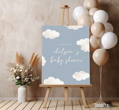 an easel with balloons in the background and a baby shower sign