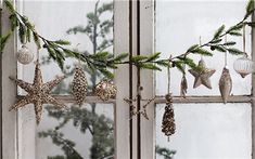 christmas decorations hanging from a window sill in front of a pine cone and starfish ornament