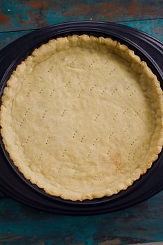 an uncooked pie crust in a black pan on a blue wooden table top