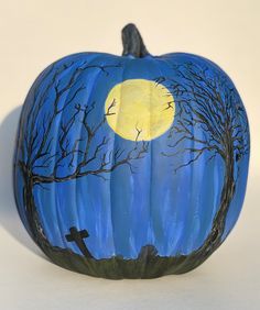 a painted pumpkin sitting on top of a white table next to a black bird and tree