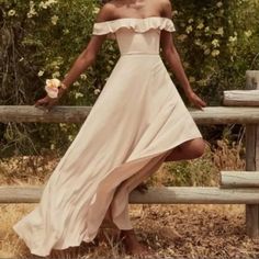 a woman in a dress leaning on a fence