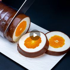 a person cutting an orange slice into pieces with a knife on a white plate next to them