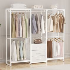 an open closet with clothes hanging on the rails and drawers, in front of a white wall