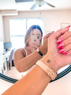 a woman taking a selfie in front of a mirror with her cell phone and pink nail polish