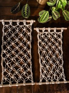 two pieces of string art hanging on a wooden wall next to a potted plant