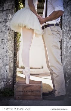 a man and woman standing next to each other in front of an arch holding hands