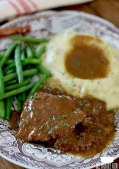 a plate with mashed potatoes, gravy and green beans