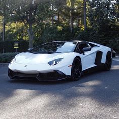 a white and black sports car parked on the side of the road in front of some trees