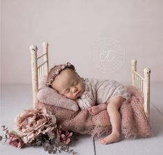 a baby sleeping on top of a pink blanket in a chair with flowers around it