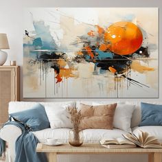 an abstract painting on the wall above a white couch with blue and orange pillows in front of it