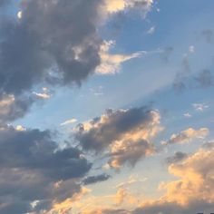 the airplane is flying high in the sky with some clouds above it and buildings below