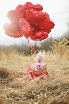 a baby is sitting in a basket with red balloons attached to the back of it